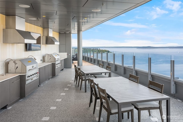 view of patio / terrace featuring a water view, area for grilling, and a bar