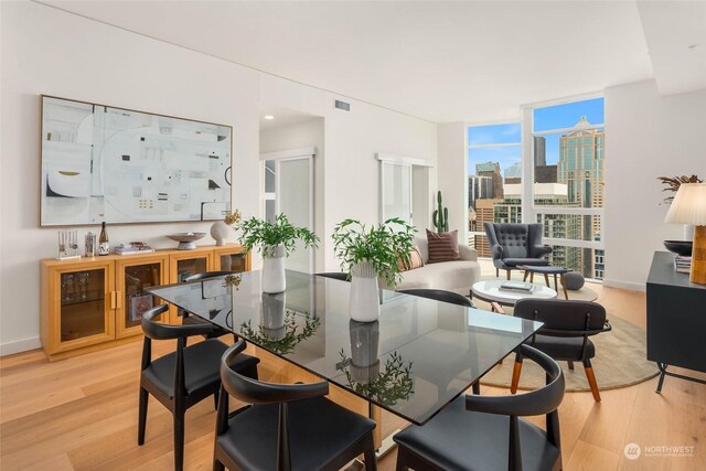 dining space with a wall of windows and light wood-type flooring