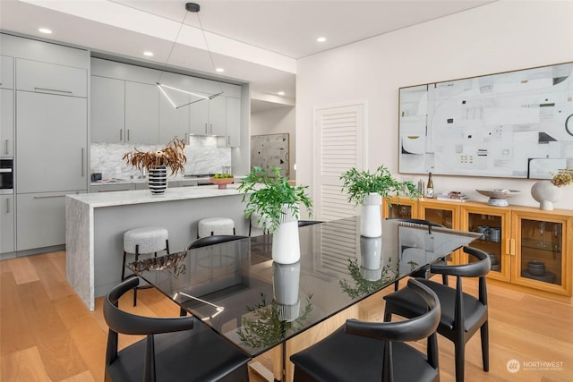 bar featuring tasteful backsplash, paneled built in refrigerator, gray cabinets, and light wood-type flooring