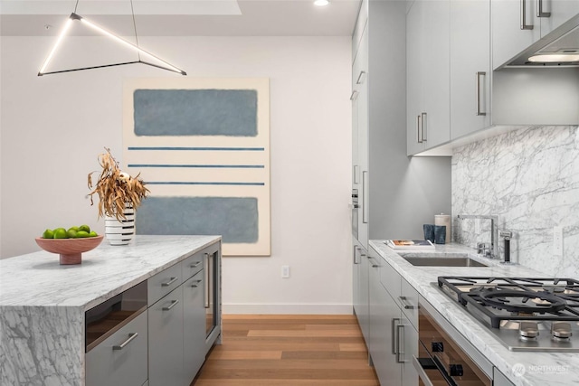 kitchen with tasteful backsplash, extractor fan, light stone counters, and stainless steel gas cooktop