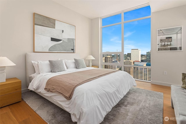 bedroom featuring hardwood / wood-style flooring and a wall of windows