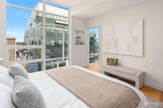 bedroom featuring multiple windows, floor to ceiling windows, and hardwood / wood-style flooring