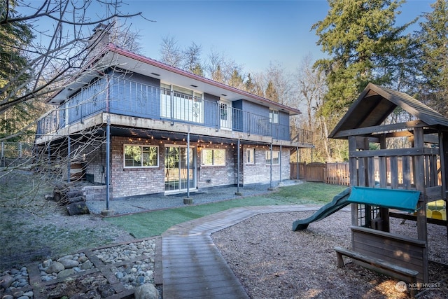 rear view of property with a playground and a yard