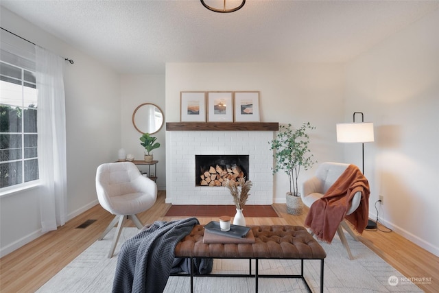 sitting room with a fireplace, hardwood / wood-style floors, and a textured ceiling