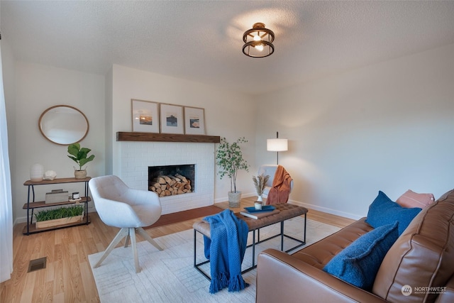 living room featuring a textured ceiling, a fireplace, and light hardwood / wood-style flooring