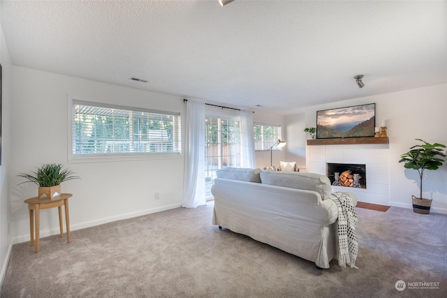 living room featuring a fireplace, a textured ceiling, and carpet