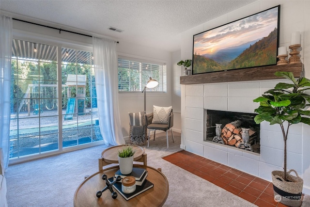 carpeted living room featuring a tiled fireplace and a textured ceiling