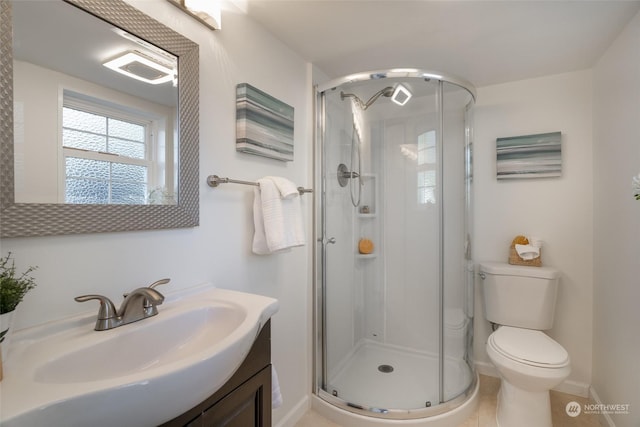 bathroom with tile patterned floors, vanity, toilet, and a shower with door