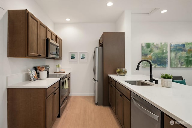 kitchen featuring a sink, recessed lighting, stainless steel appliances, light wood finished floors, and light countertops