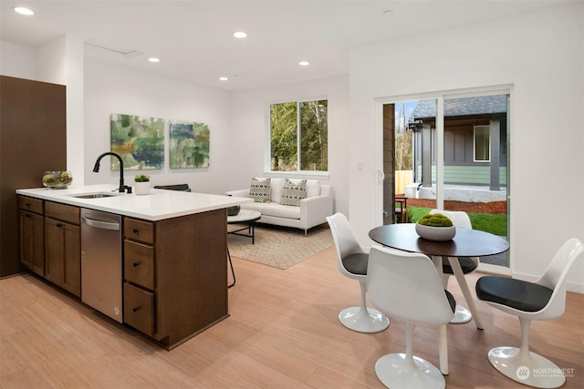 kitchen featuring recessed lighting, a sink, light countertops, dishwasher, and light wood-type flooring