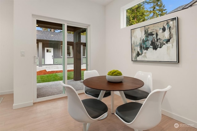 dining room with plenty of natural light, baseboards, and light wood finished floors