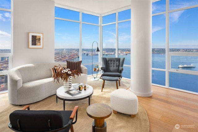 living area featuring hardwood / wood-style flooring, a water view, plenty of natural light, and a wall of windows