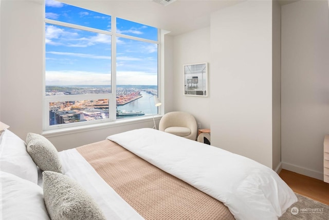 bedroom with hardwood / wood-style flooring and a water view