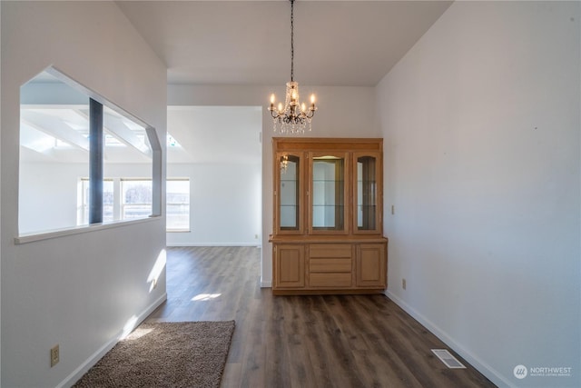 unfurnished dining area with dark hardwood / wood-style flooring and a chandelier