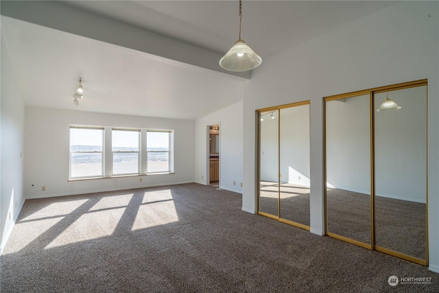 unfurnished bedroom with lofted ceiling, carpet, and two closets