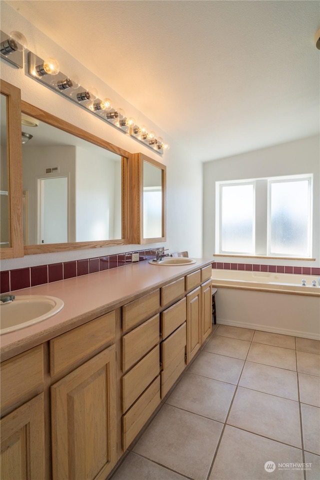 bathroom with tile patterned flooring, vanity, and a bath