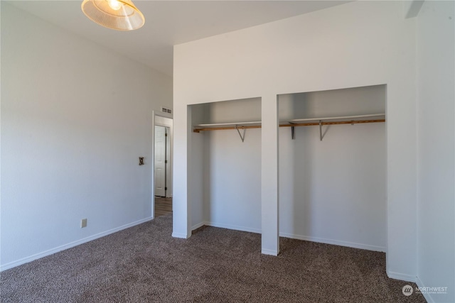 unfurnished bedroom featuring two closets and dark colored carpet