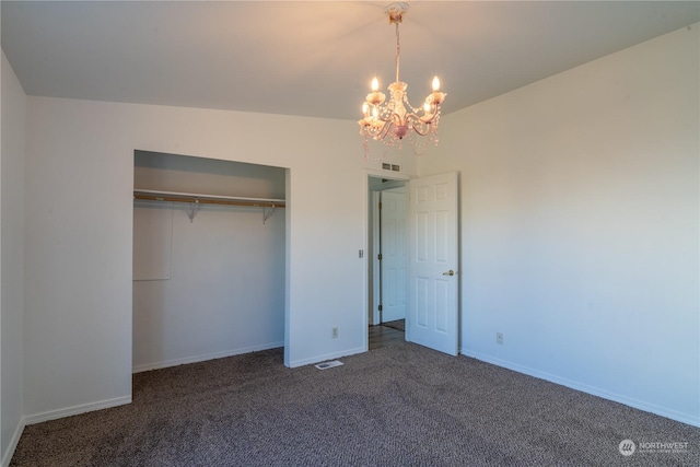 unfurnished bedroom featuring a chandelier, dark carpet, and a closet