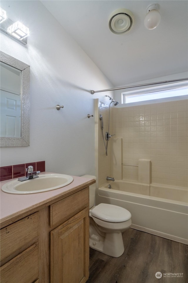 full bathroom featuring shower / bath combination, hardwood / wood-style floors, vanity, vaulted ceiling, and toilet