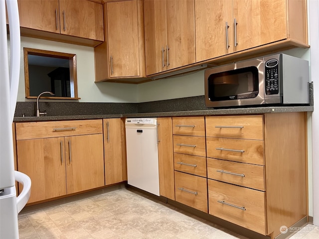 kitchen featuring appliances with stainless steel finishes, sink, and dark stone countertops