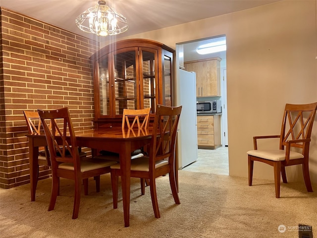 dining space featuring brick wall, a chandelier, and light carpet