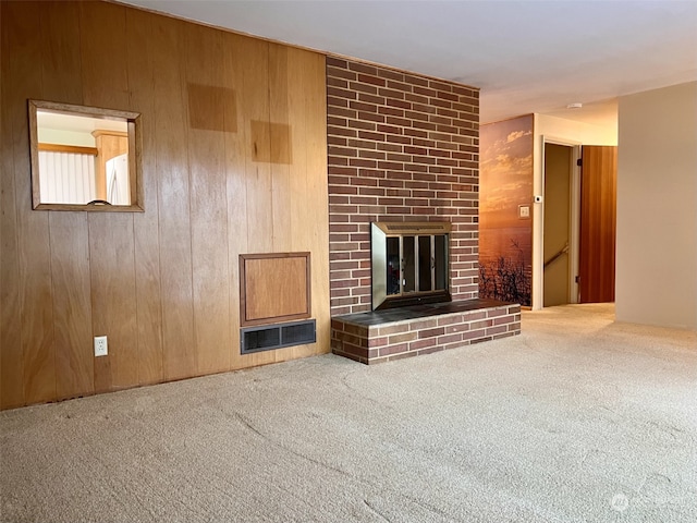 unfurnished living room featuring carpet flooring, a fireplace, and wood walls