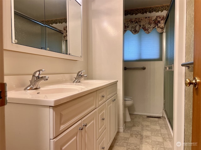 bathroom with vanity, a shower with door, and toilet