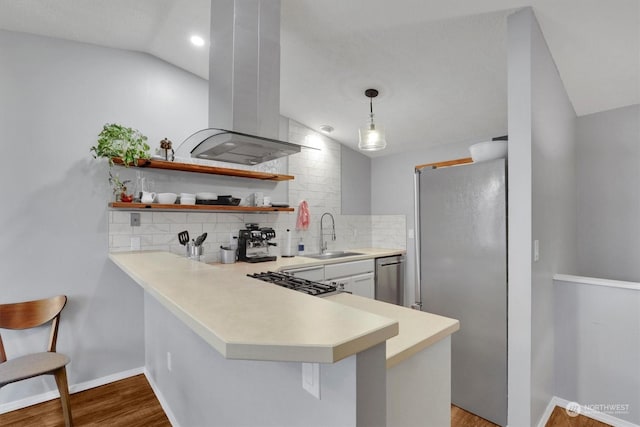 kitchen with stainless steel appliances, island exhaust hood, lofted ceiling, and kitchen peninsula