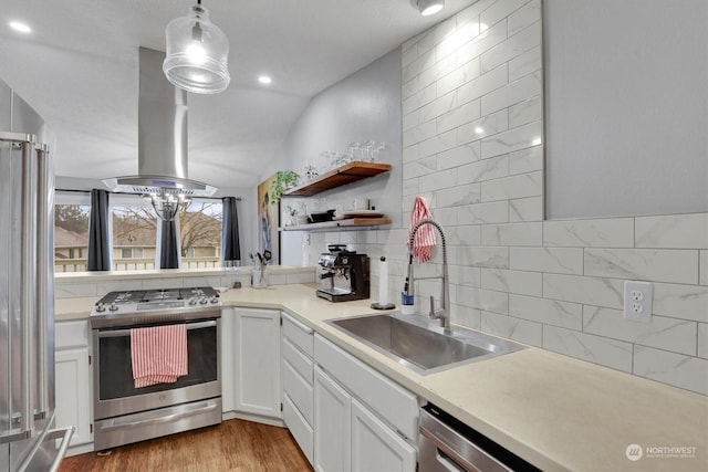 kitchen with sink, white cabinetry, appliances with stainless steel finishes, pendant lighting, and island exhaust hood