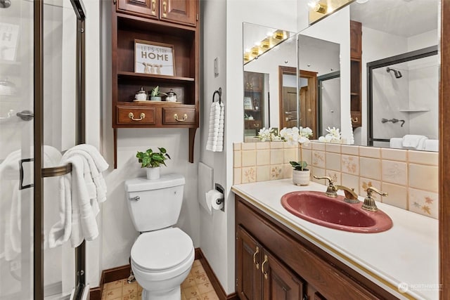 bathroom with a shower with door, vanity, toilet, and decorative backsplash