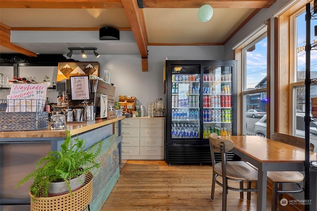 bar with stainless steel fridge and light hardwood / wood-style flooring