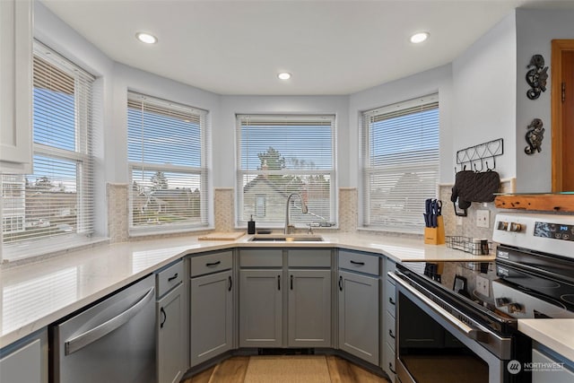 kitchen with stainless steel appliances, gray cabinets, sink, and plenty of natural light