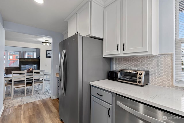 kitchen featuring light stone countertops, white cabinetry, appliances with stainless steel finishes, and light hardwood / wood-style flooring