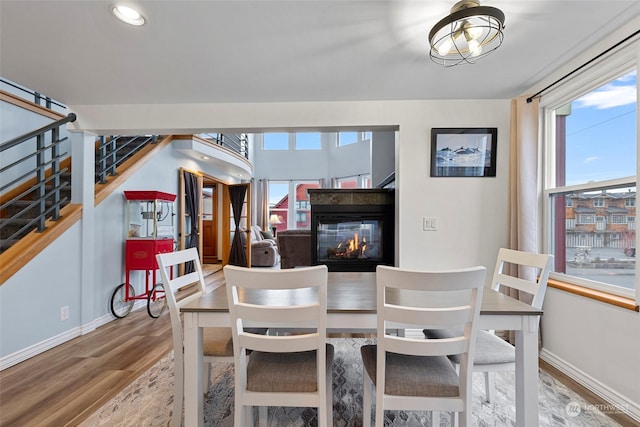 dining space with hardwood / wood-style flooring and a multi sided fireplace