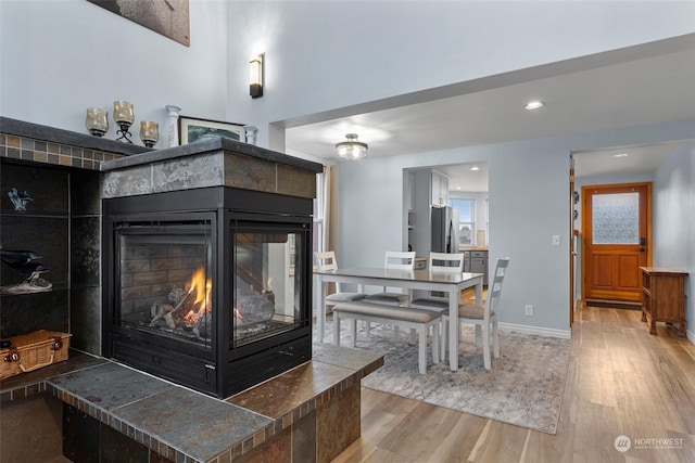 interior details with hardwood / wood-style floors, stainless steel refrigerator, and a multi sided fireplace