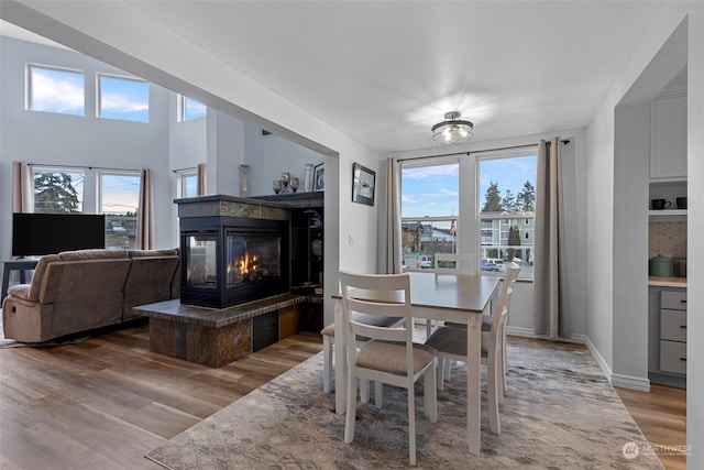 dining room with a multi sided fireplace, hardwood / wood-style floors, and a wealth of natural light