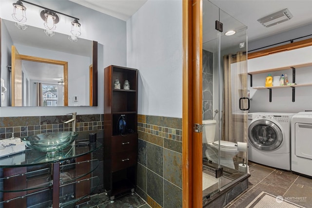 bathroom featuring washing machine and dryer, tile walls, vanity, and toilet