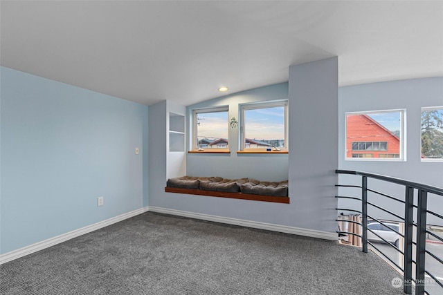 unfurnished room with lofted ceiling, built in shelves, and carpet flooring