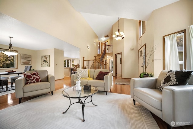 living room featuring an inviting chandelier, a towering ceiling, and light hardwood / wood-style floors