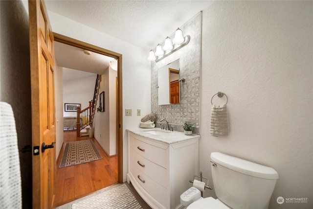 bathroom featuring vanity, wood-type flooring, a textured ceiling, and toilet