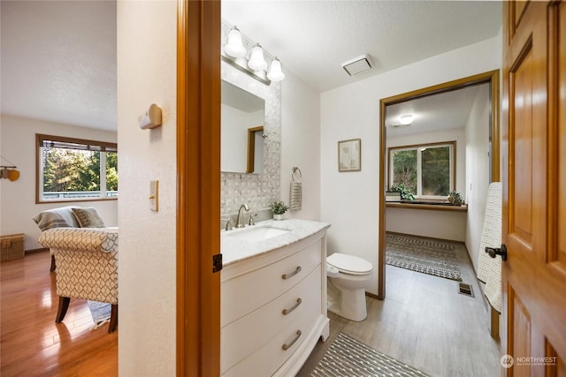 bathroom with vanity, wood-type flooring, backsplash, and toilet