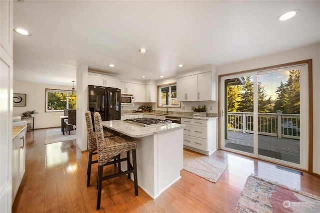 kitchen featuring sink, stainless steel appliances, light hardwood / wood-style floors, white cabinets, and a kitchen island