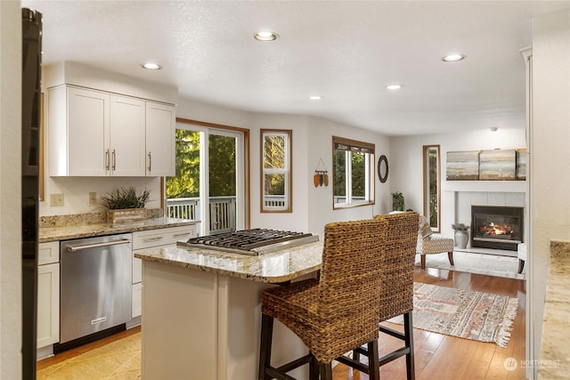 kitchen with a breakfast bar area, white cabinets, a center island, light stone counters, and stainless steel appliances