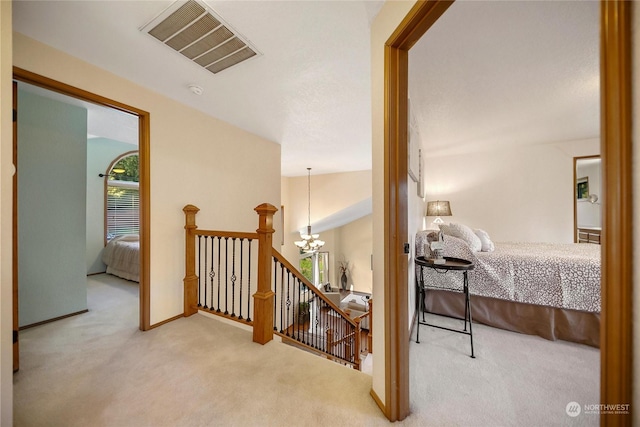 hall with a notable chandelier, plenty of natural light, light colored carpet, and vaulted ceiling