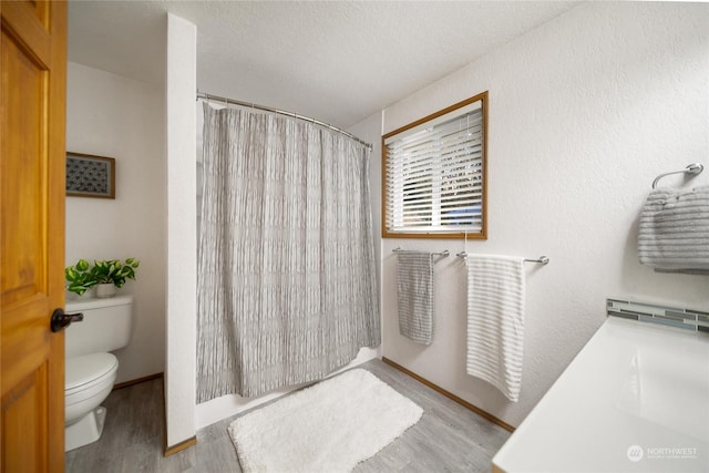 bathroom featuring wood-type flooring, toilet, a shower with shower curtain, and a textured ceiling