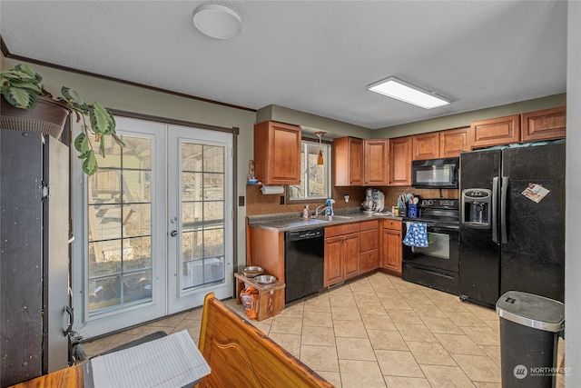 kitchen featuring light tile patterned floors, a sink, french doors, brown cabinets, and black appliances