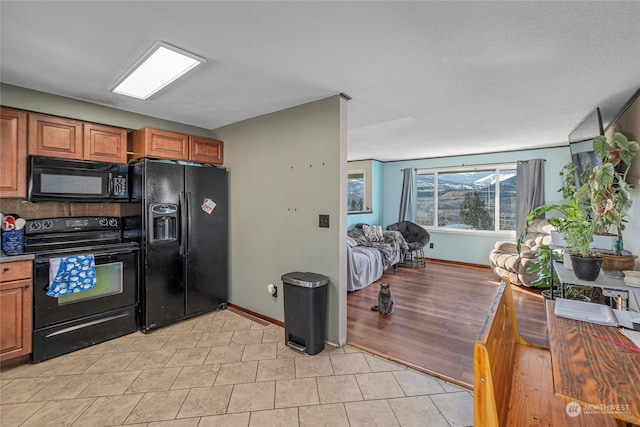 kitchen featuring black appliances, light tile patterned floors, baseboards, and brown cabinets