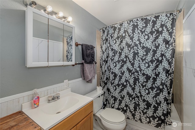 bathroom featuring curtained shower, a textured wall, vanity, and toilet