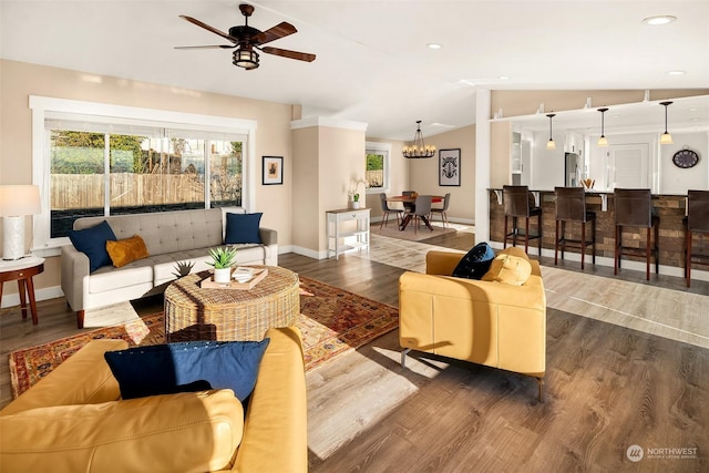 living area featuring lofted ceiling, recessed lighting, ceiling fan with notable chandelier, wood finished floors, and baseboards