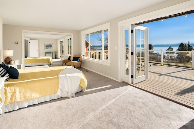 bedroom featuring baseboards, a water view, access to exterior, carpet floors, and a closet